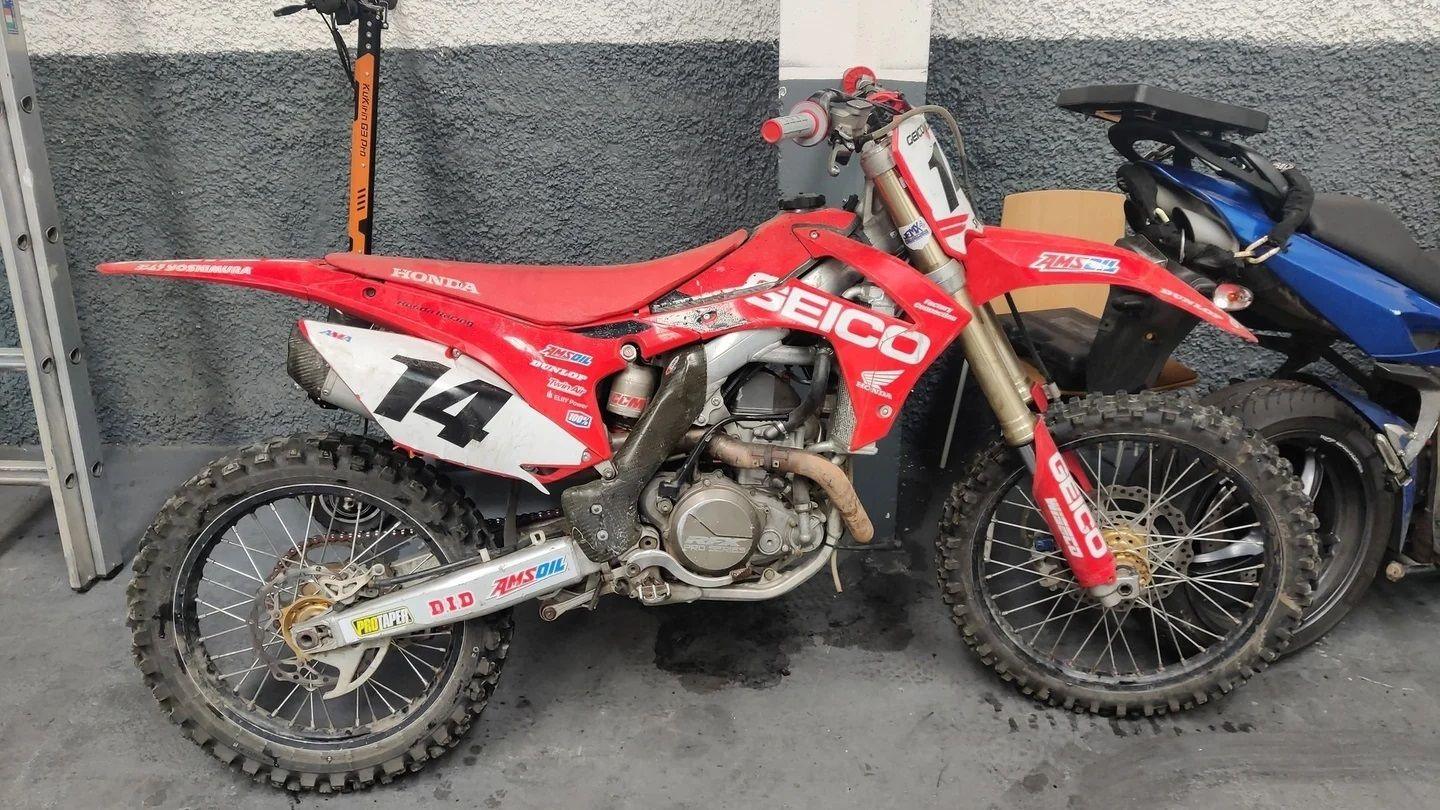 Red scrambler bike against a grey wall, blue scrambler bike visible on right hand side