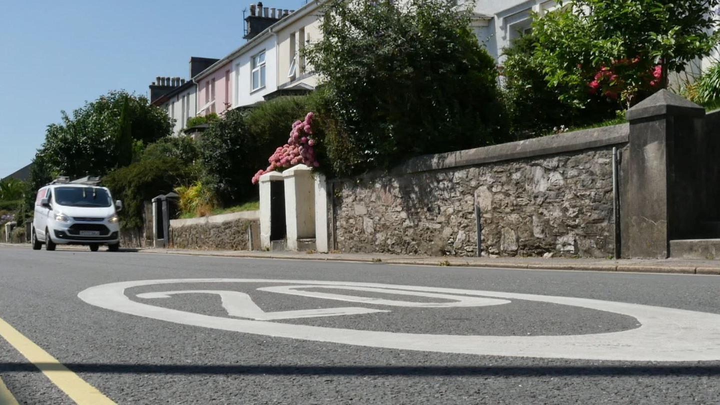 A road with a large 20 written in white, inside a circle, on the ground