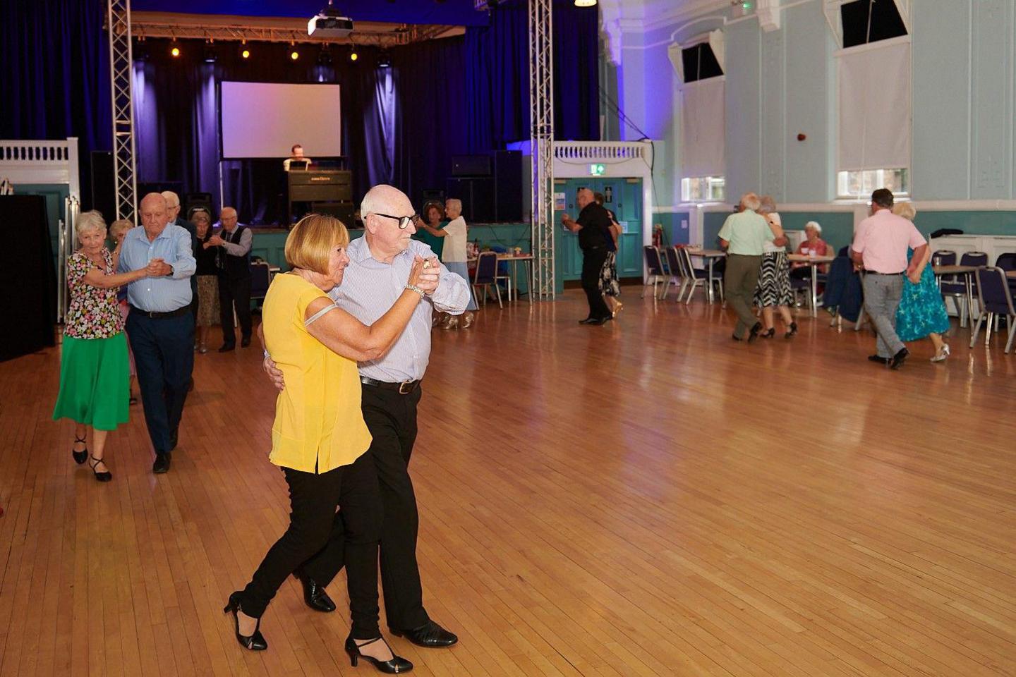 Couples dancing across the Bilston Town Hall dance floor while an organist plays in the background