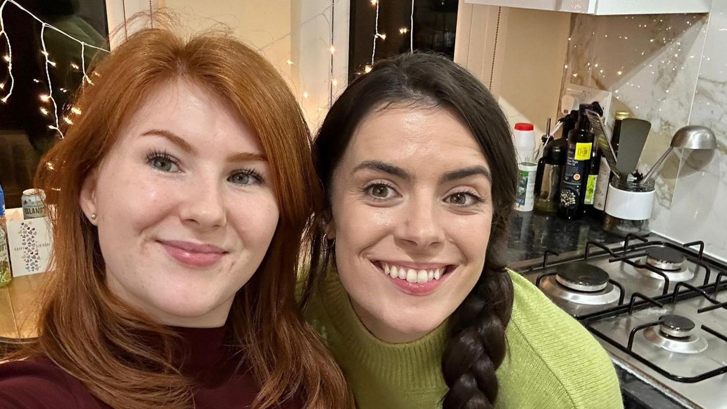 Hannah Carney and her flatmate Emma in the kitchen of their rental home, with hobs and utensils behind them.