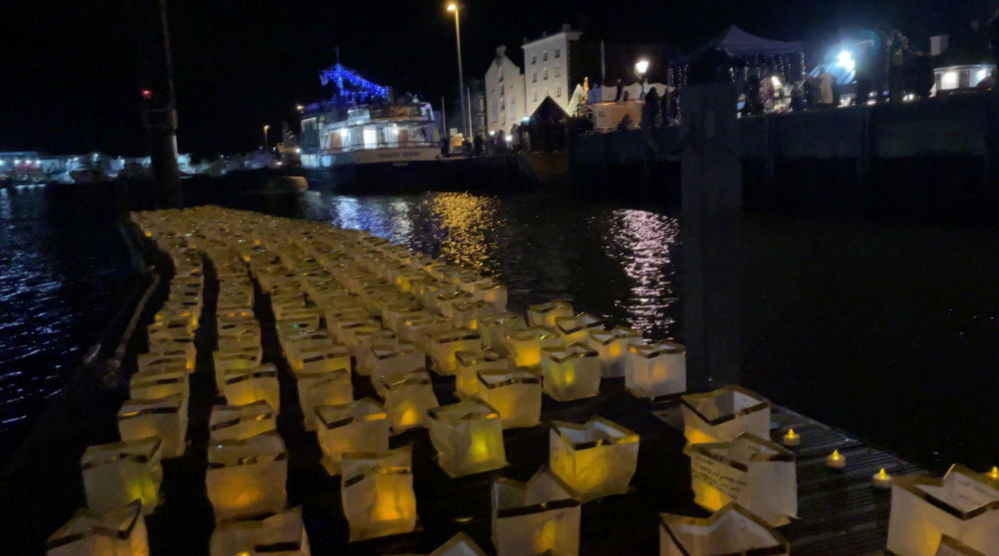 Close up image of paper lanterns and candles along the waterfront at Poole Quay.