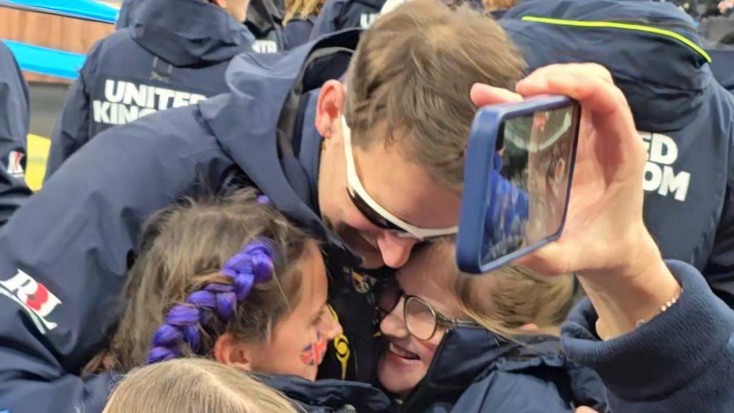 Ben hugging daughters after stepping off the podium.