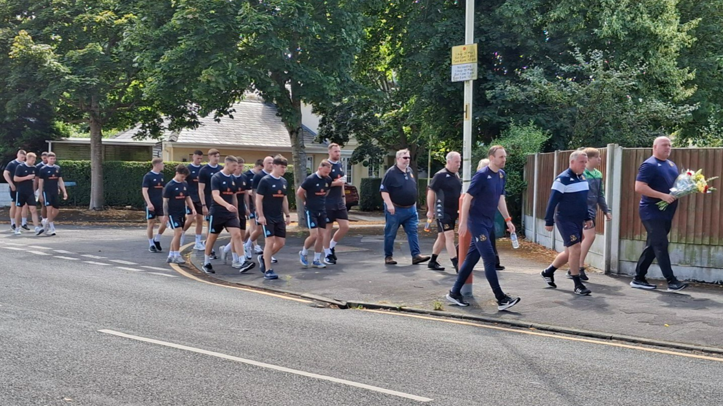 Southport's players and staff walk to the police cordon on Hart Street to pay their respects and lay flowers 