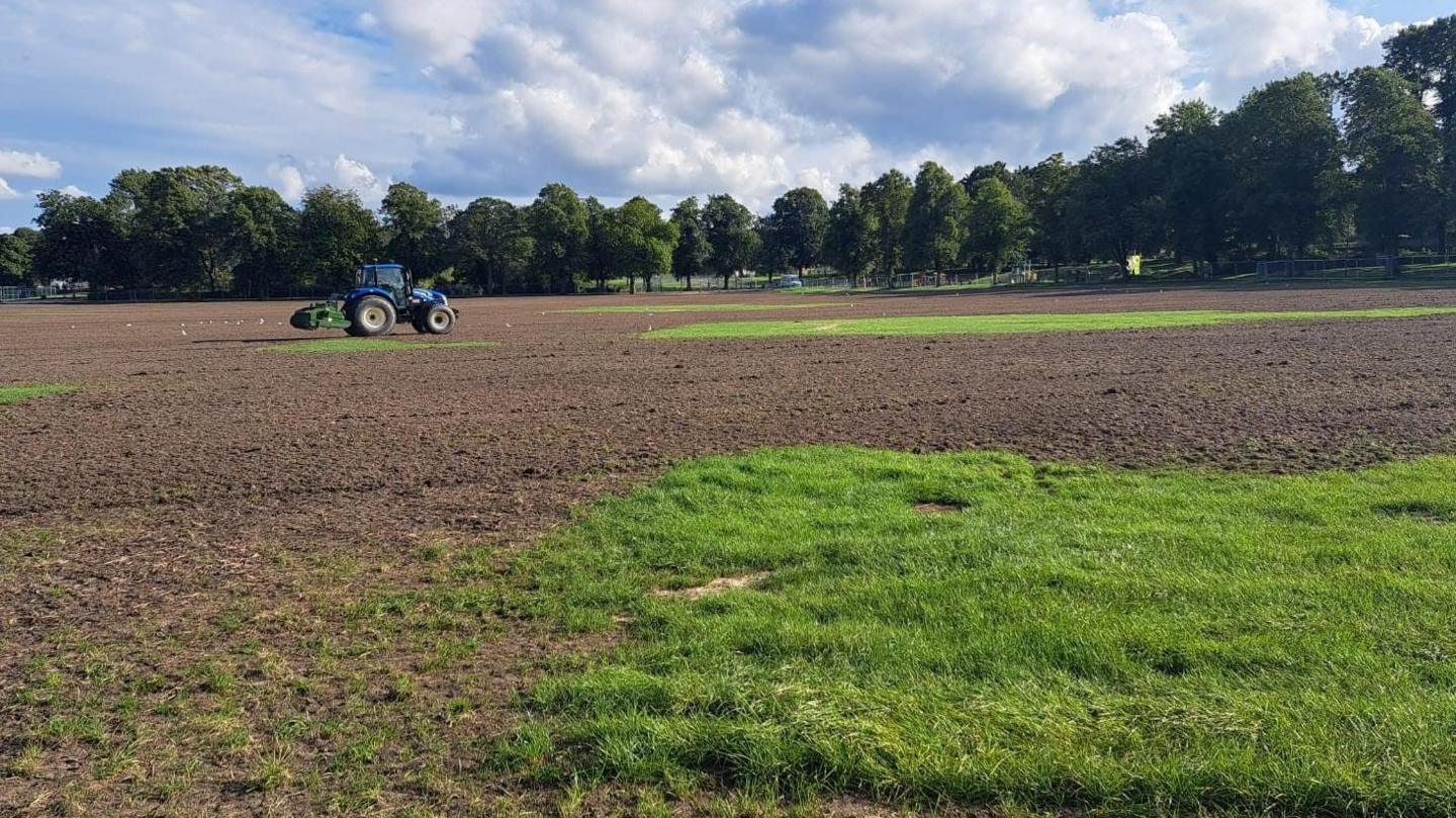 A blue tractor in the middle of a muddy field