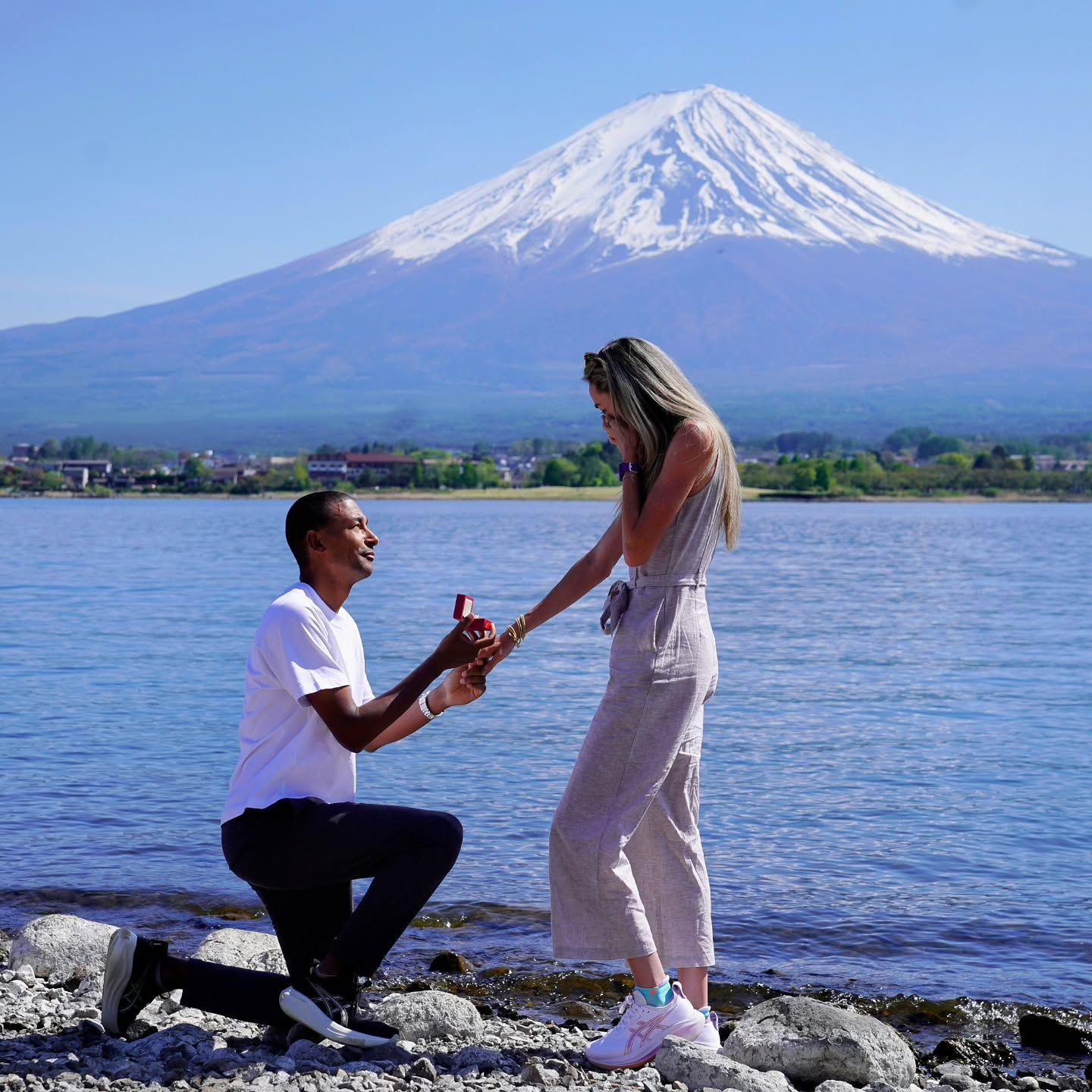 Michael Rimmer - wearing a white T-shirt and dark jeans - on one knee proposing to Eilish McColgan, who is holding a hand to her mouth in shock