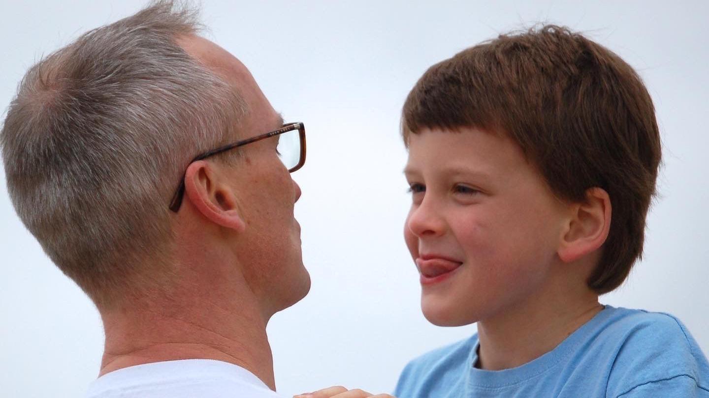 Paul O'Dwyer, with short grey hair and glasses, looking at his son Henry, a young boy with short brown hair wearing a blue shirt