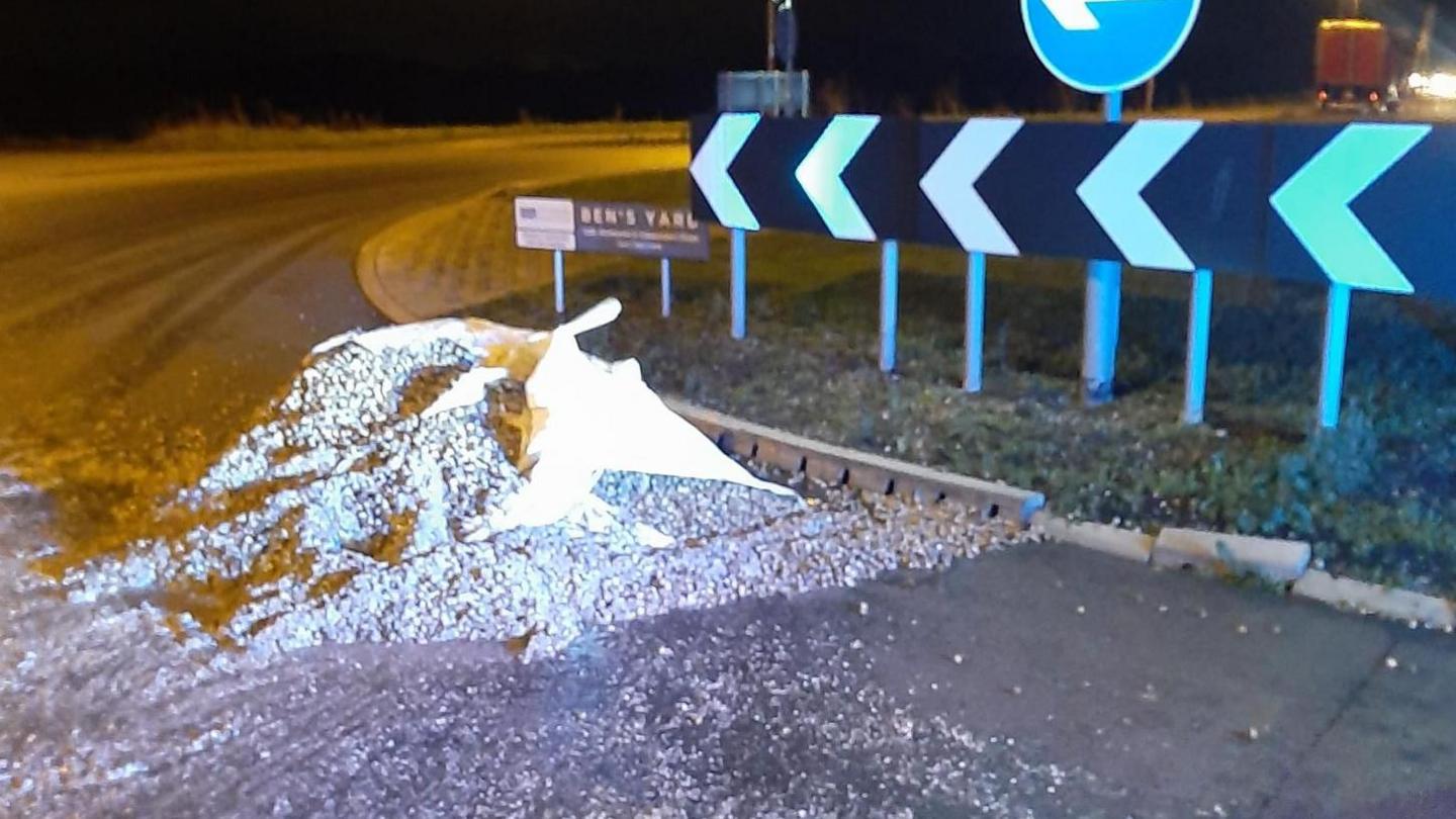 A pile of cockles spilled across a road near a roundabout.