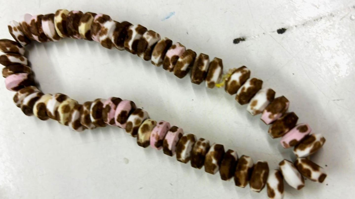 An edible pastel beaded necklace which has black mould growing all over it.