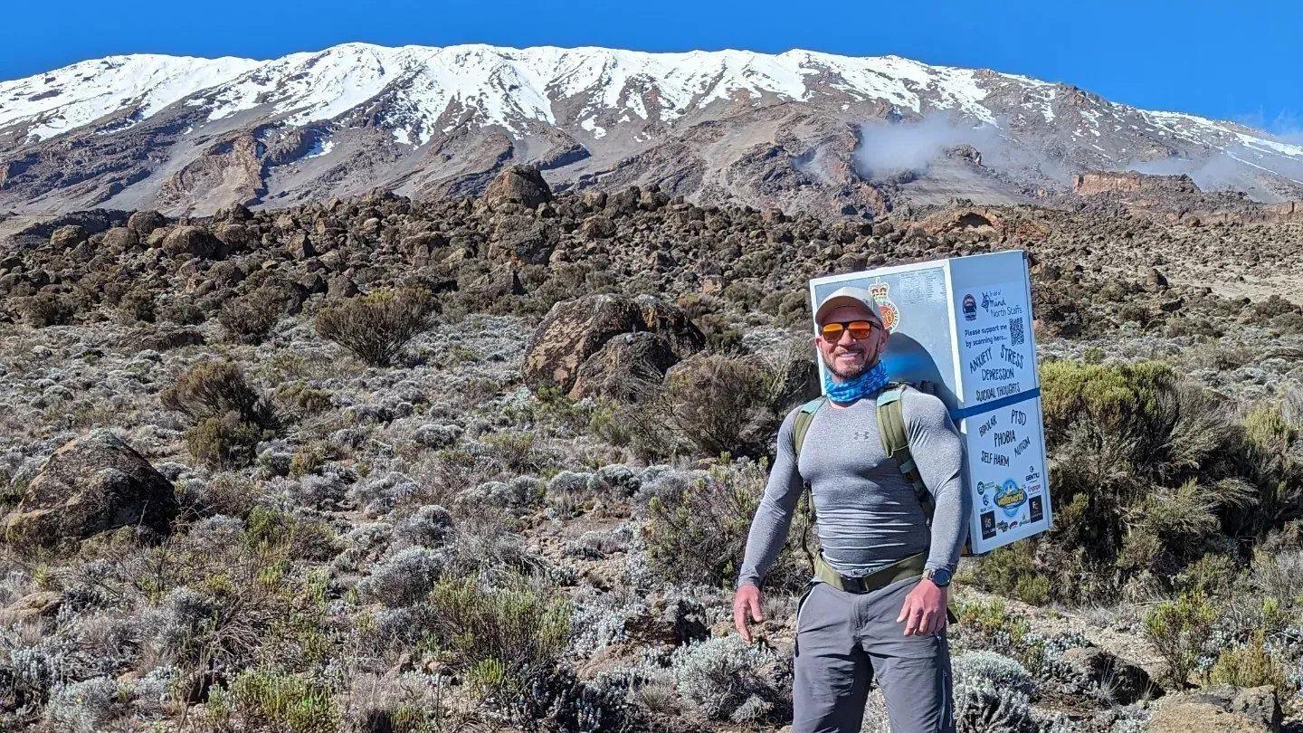 Michael Copeland carrying a fridge with Mount Kilimanjaro in the background