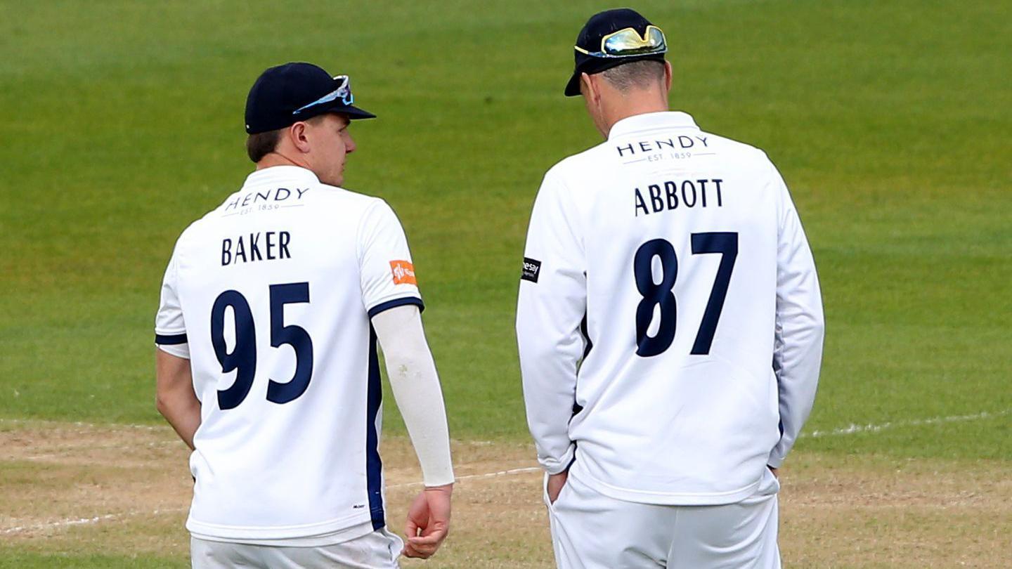 Sonny Baker and Kyle Abbott speak on the cricket field during a County Championship match