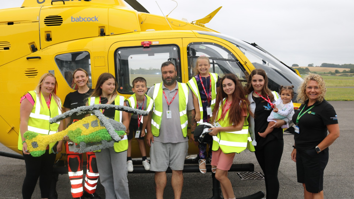 The family all wearing hi-vis jackets and standing in front of a yellow helicopter.