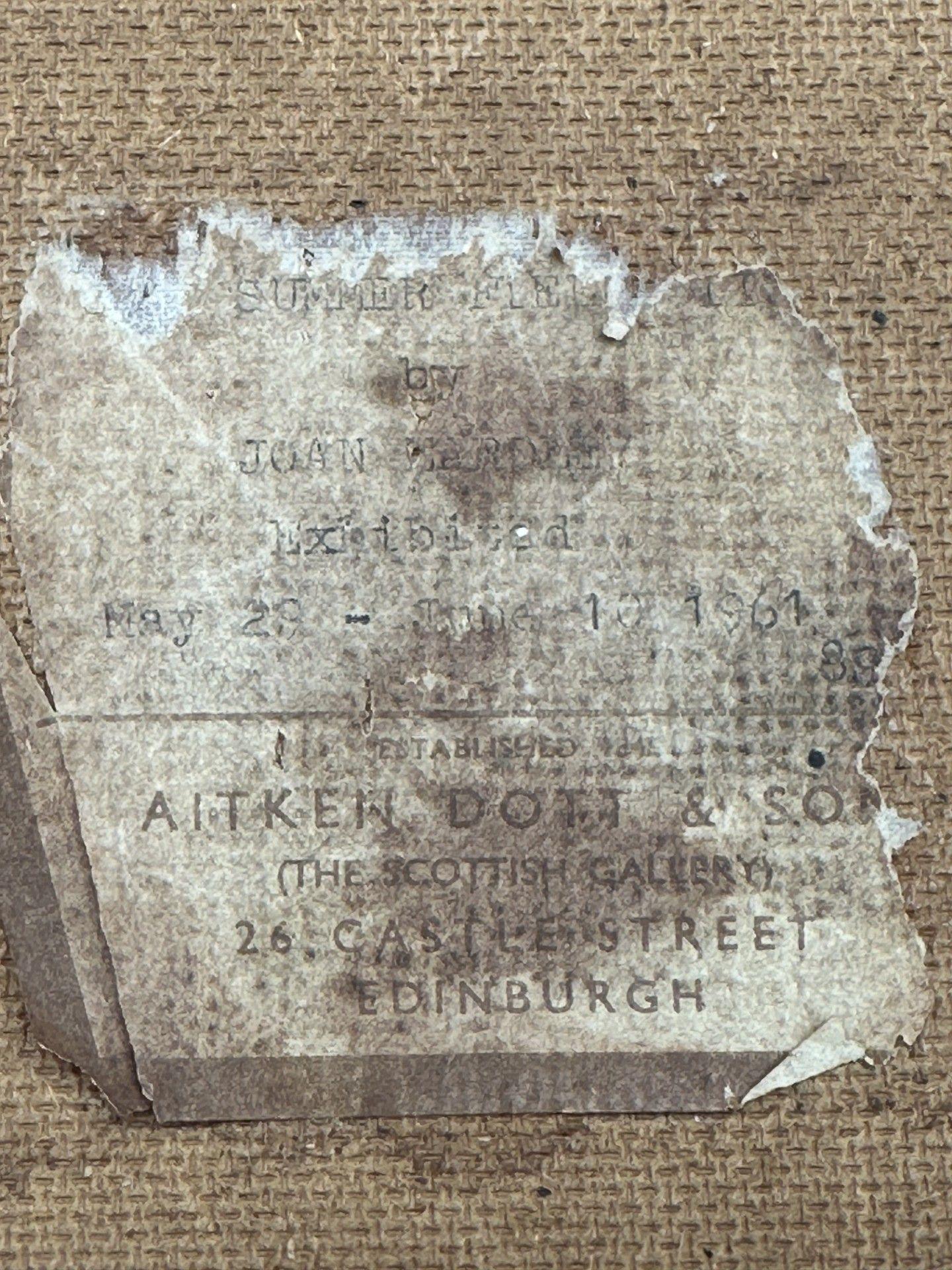 Close-up of a worn, torn label attached to the back of a canvas, with faded text