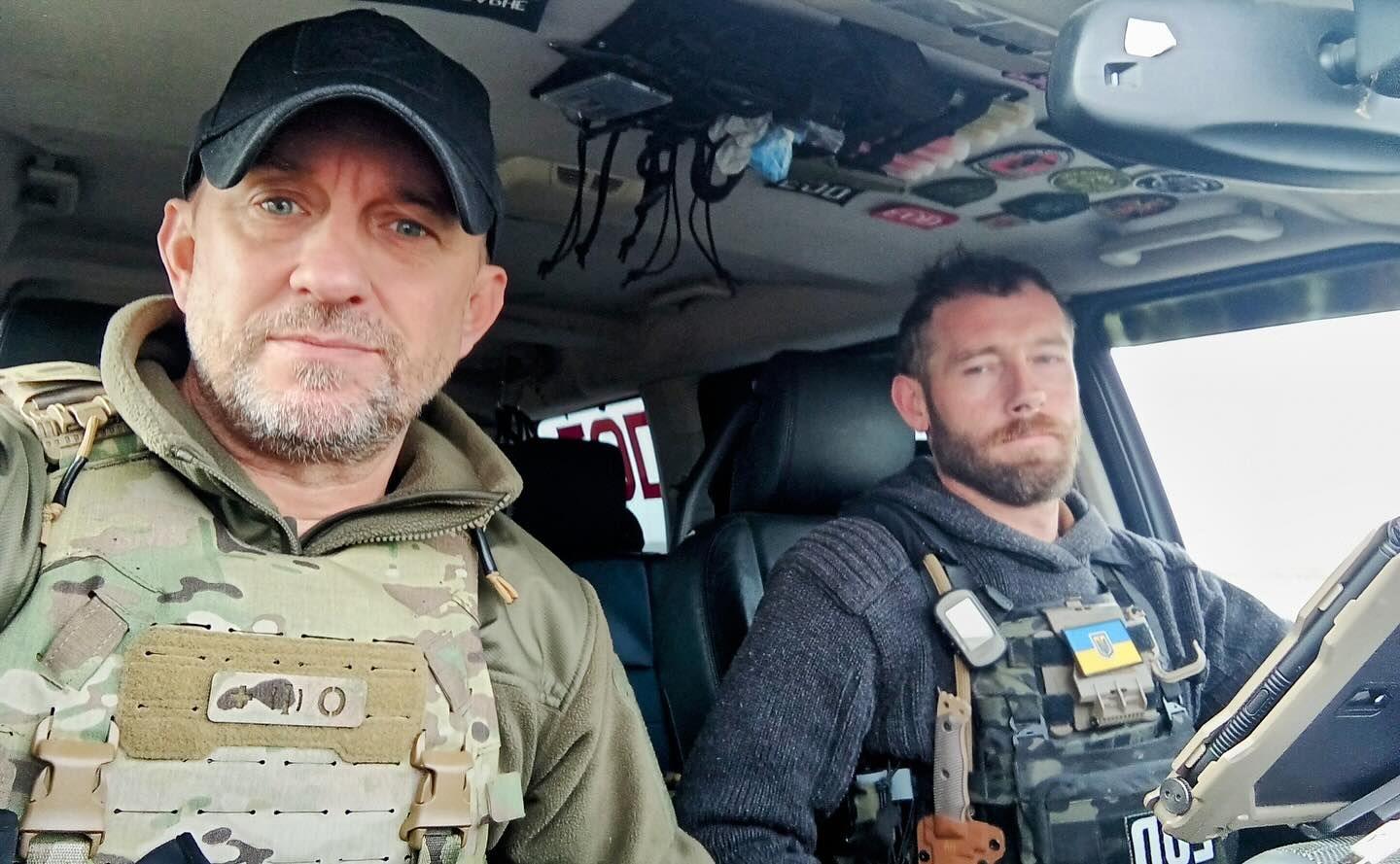 A selfie of two men Shaun Pinner, and Chris Garrett in military style vests in a car