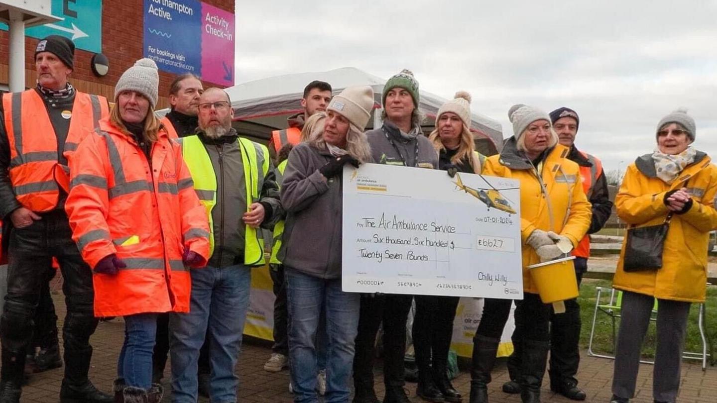 A group of people hold up a large cheque for the Air Ambulance.