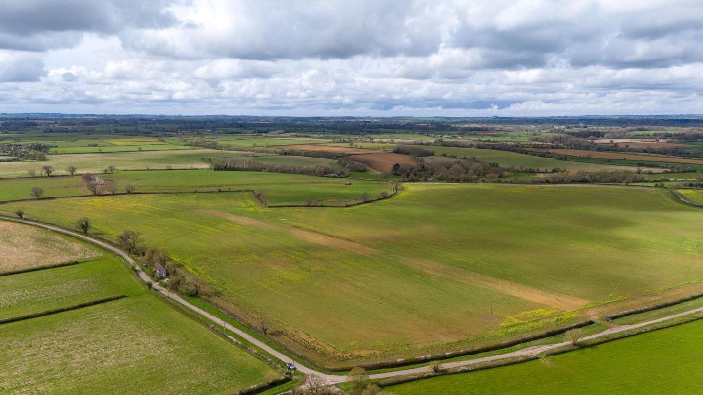 Drone shot of green countryside in north Wiltshire with fields bordered by fencing and hedgerows