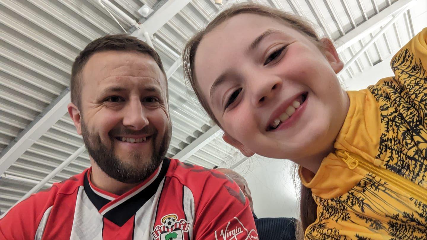 man in saints top with daughter