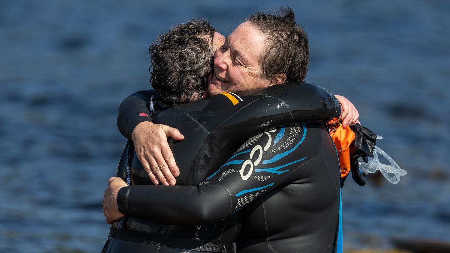 Two swimmers hug after completing the Kessock Ferry Swim