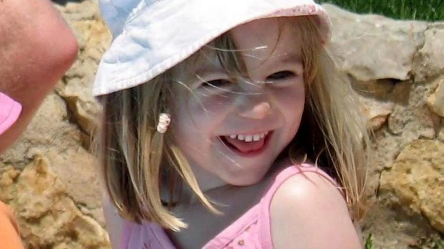 Madeleine McCann wearing a pink top and a white sun hat