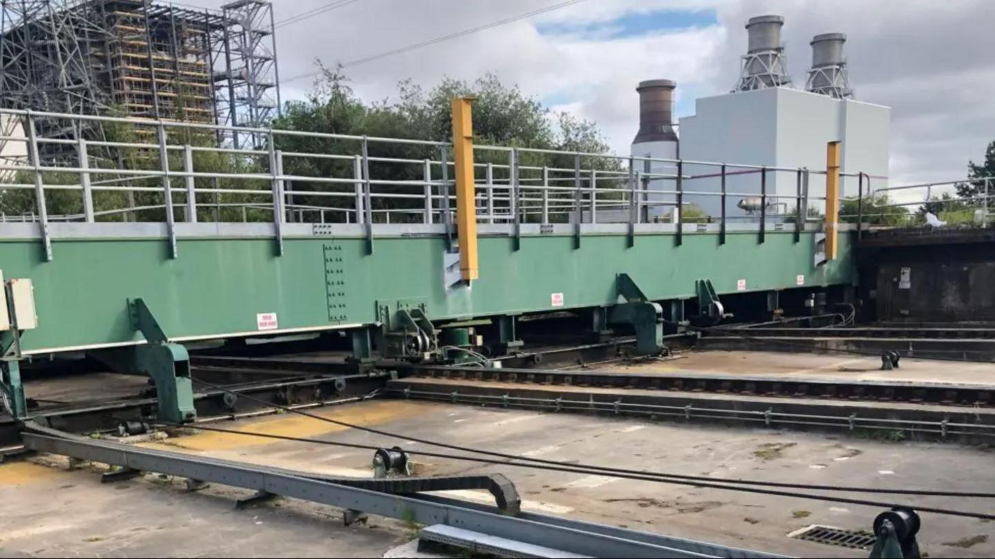 A close-up of green metal barriers going across metal tracks.