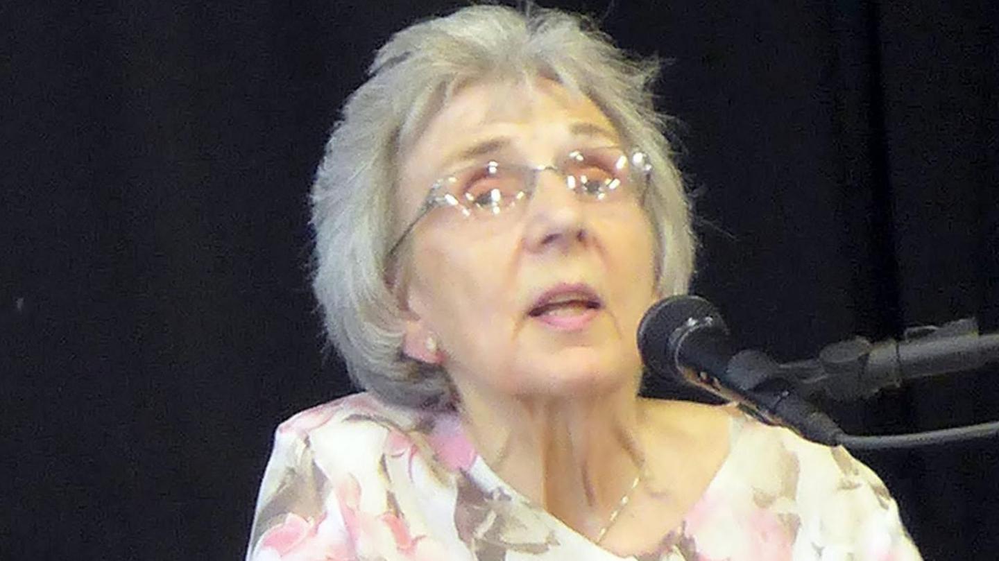 Rhian Evans yn ystod y cyfarfod yn Sanclêr yn gwisgo ffrog binc, beige a gwyn