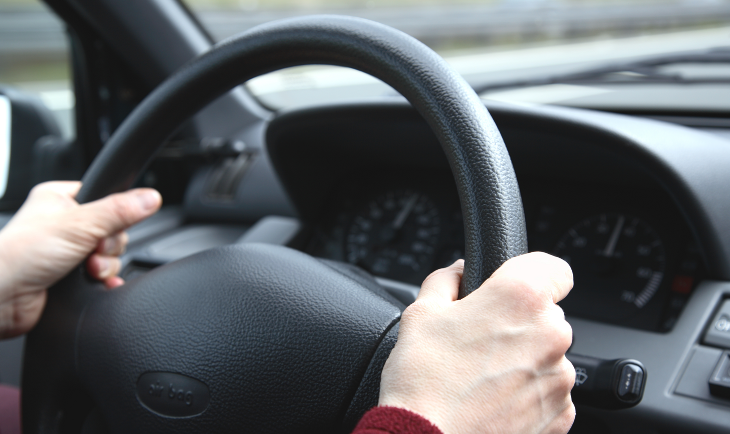 Hands holding steering wheel