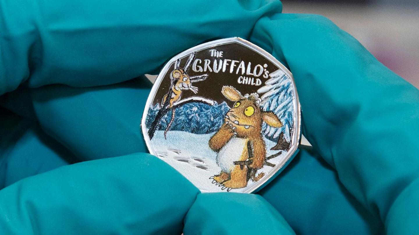 Gloved hands holding the colour Gruffalo coin