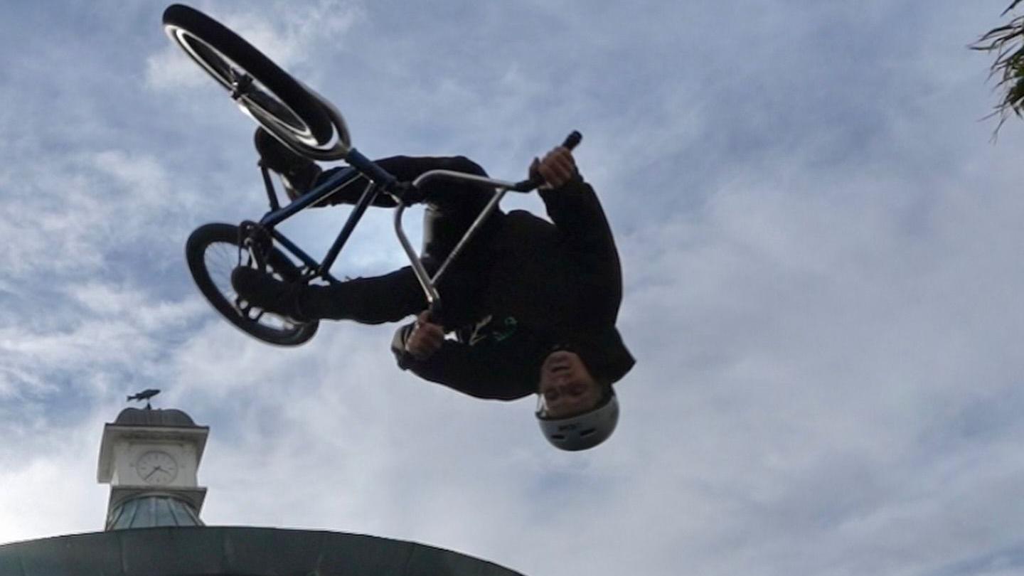 A BMX rider performing a trick and flying in the sky