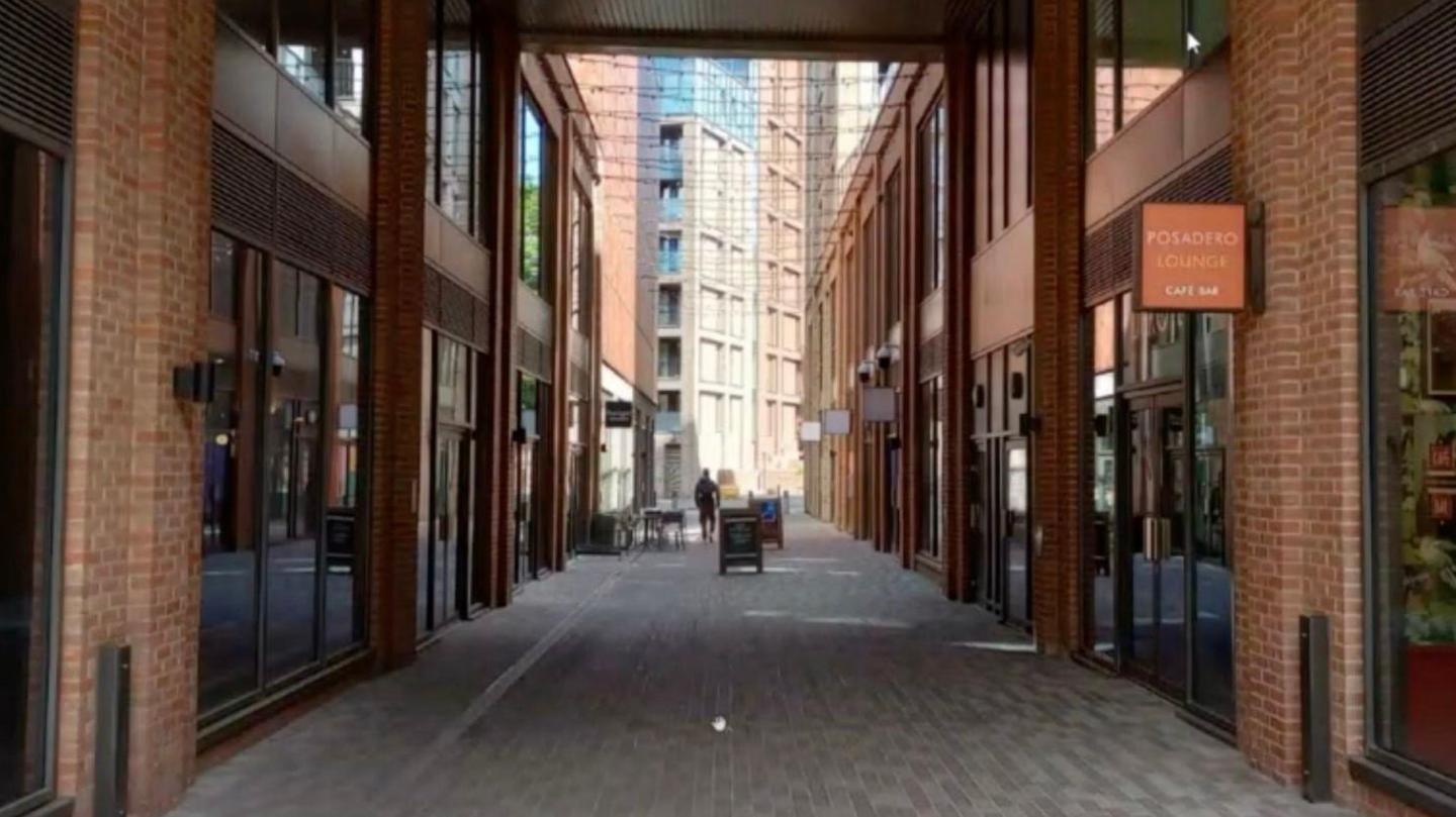 An alley in a new-build complex with shop sites either side.