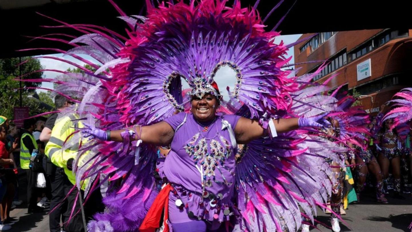 A woman wears a huge purple costume with loads of purple feathers