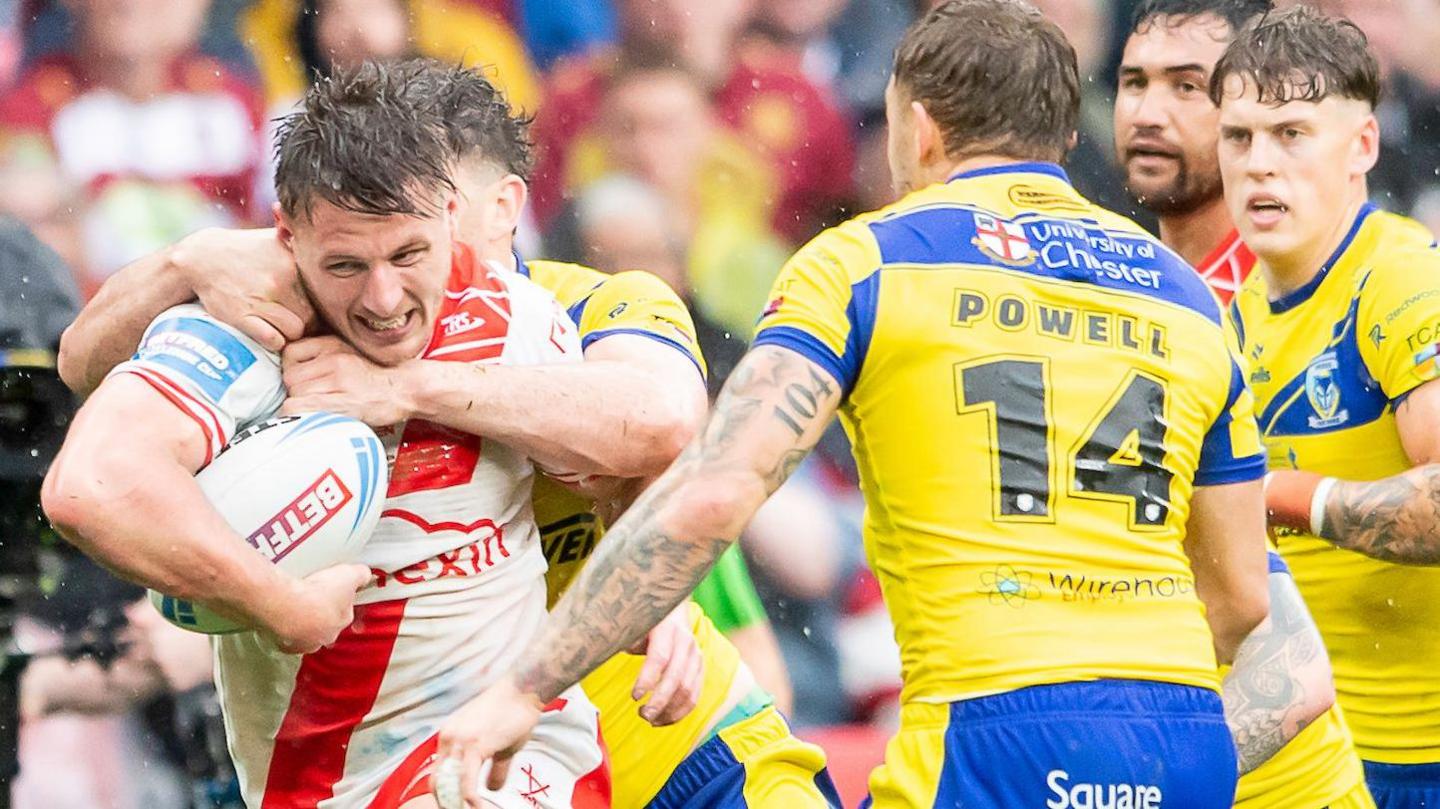 Hull KR winger Tom Davies has the ball in his left arm as he tries to ride the tackles of Jordy Crowther and Sam Powell for Warrington in the 2025 Challenge Cup final.