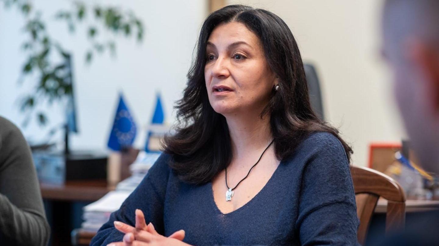 Ivanna Klympush-Tsyntsadze, sitting down, is wearing a dark blue dress and a silver pendant. 