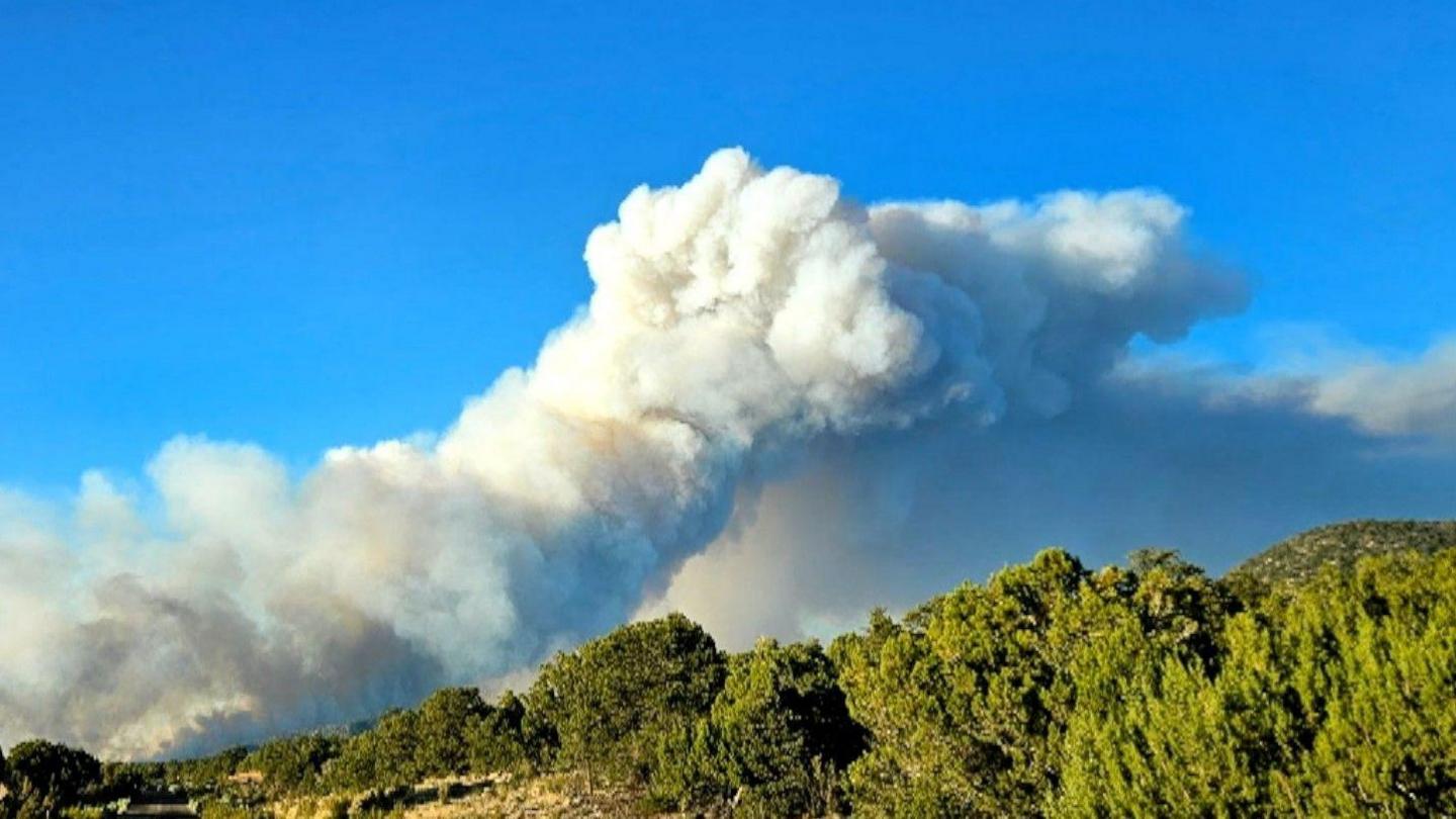 Picture of smoke rising over the mountains at Arizona fire with a blue sky in the background