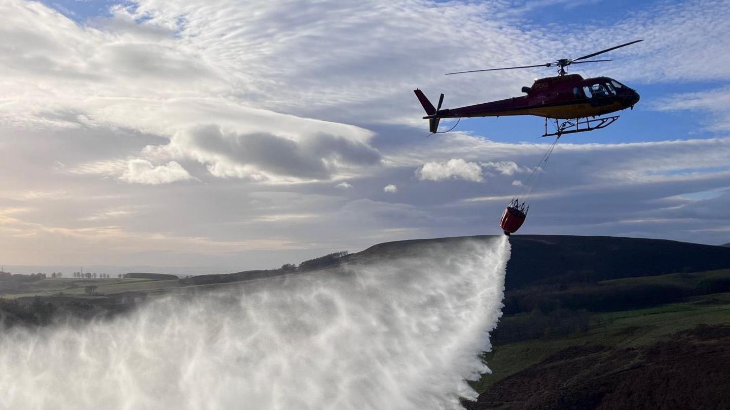 A helicopter demonstrates water bombing on a moorland in Aberdeenshire