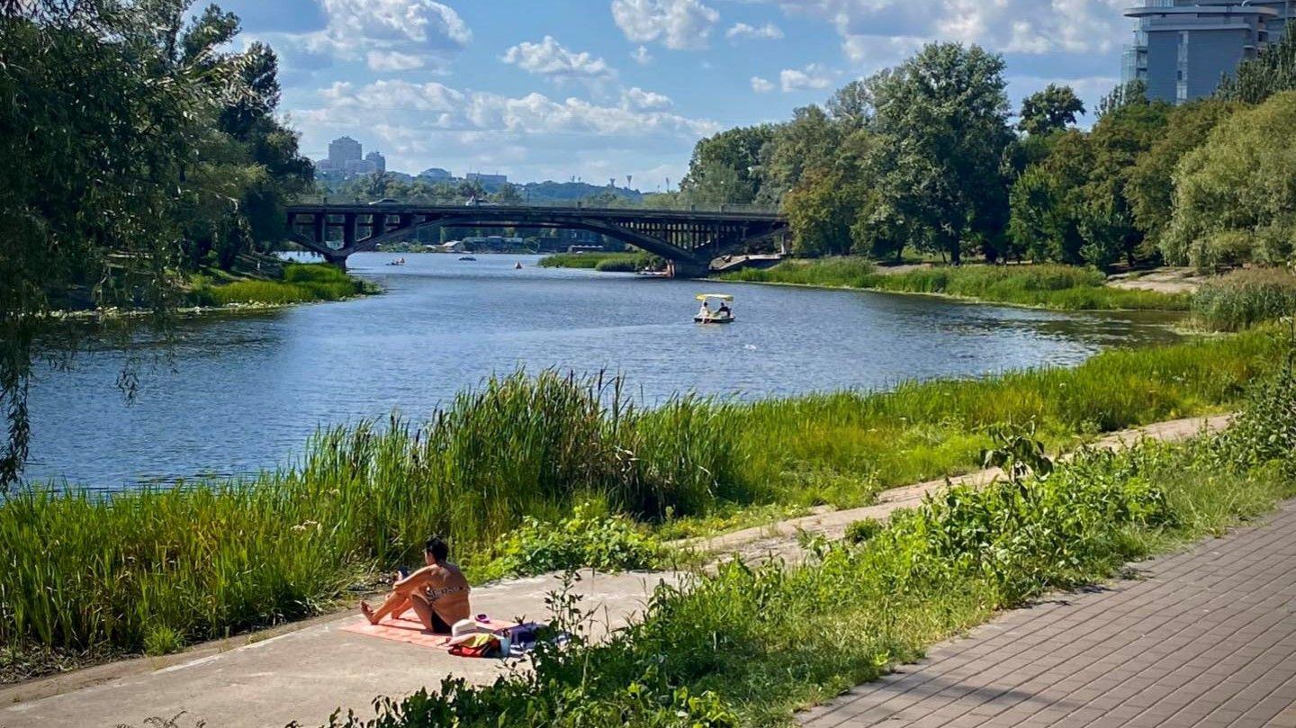A view of the river banks of the Dnieper, with a woman relaxing in the sun.