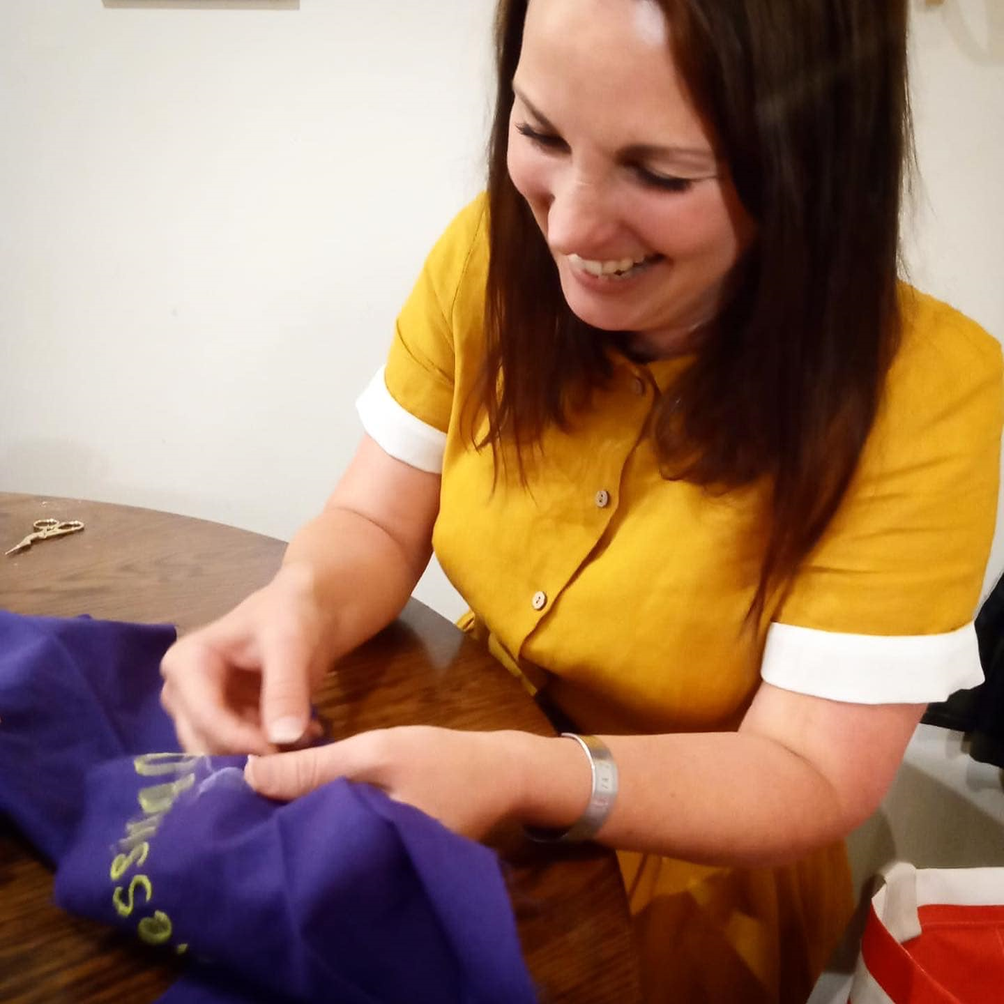 A photograph of Laura Burrill stitching the quilt. She is wearing a yellow top