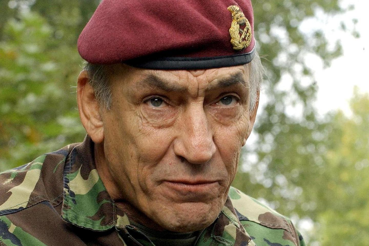 General Sir Mike Jackson is photographed close-up in combat gear against a background of trees. He has a maroon army beret and a camouflage jacket. He is looking intently beyond the camera, his face lined and craggy. 