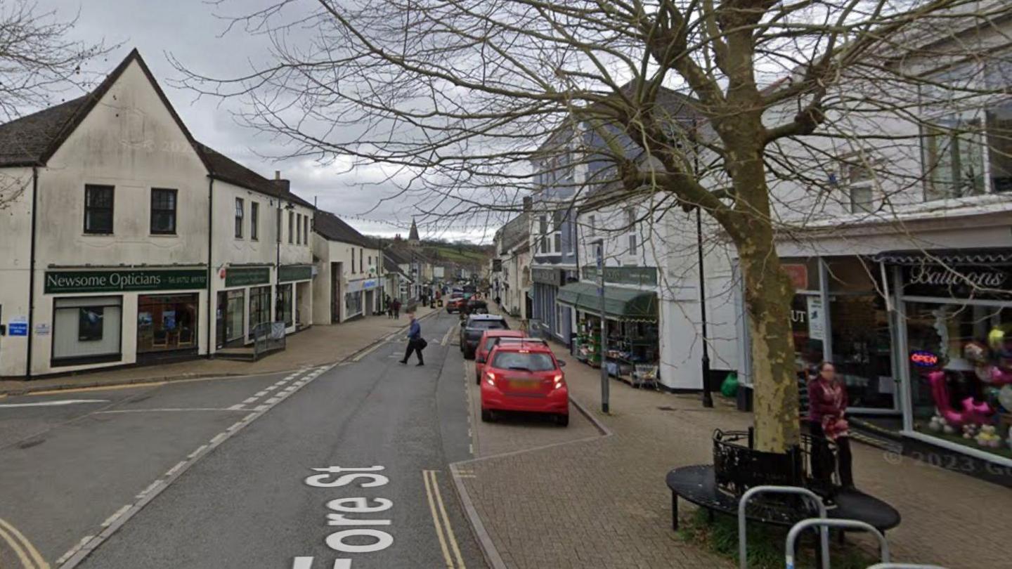 A picture of Ivybridge town high street. There is a road in the centre and is surrounded by shops either side.