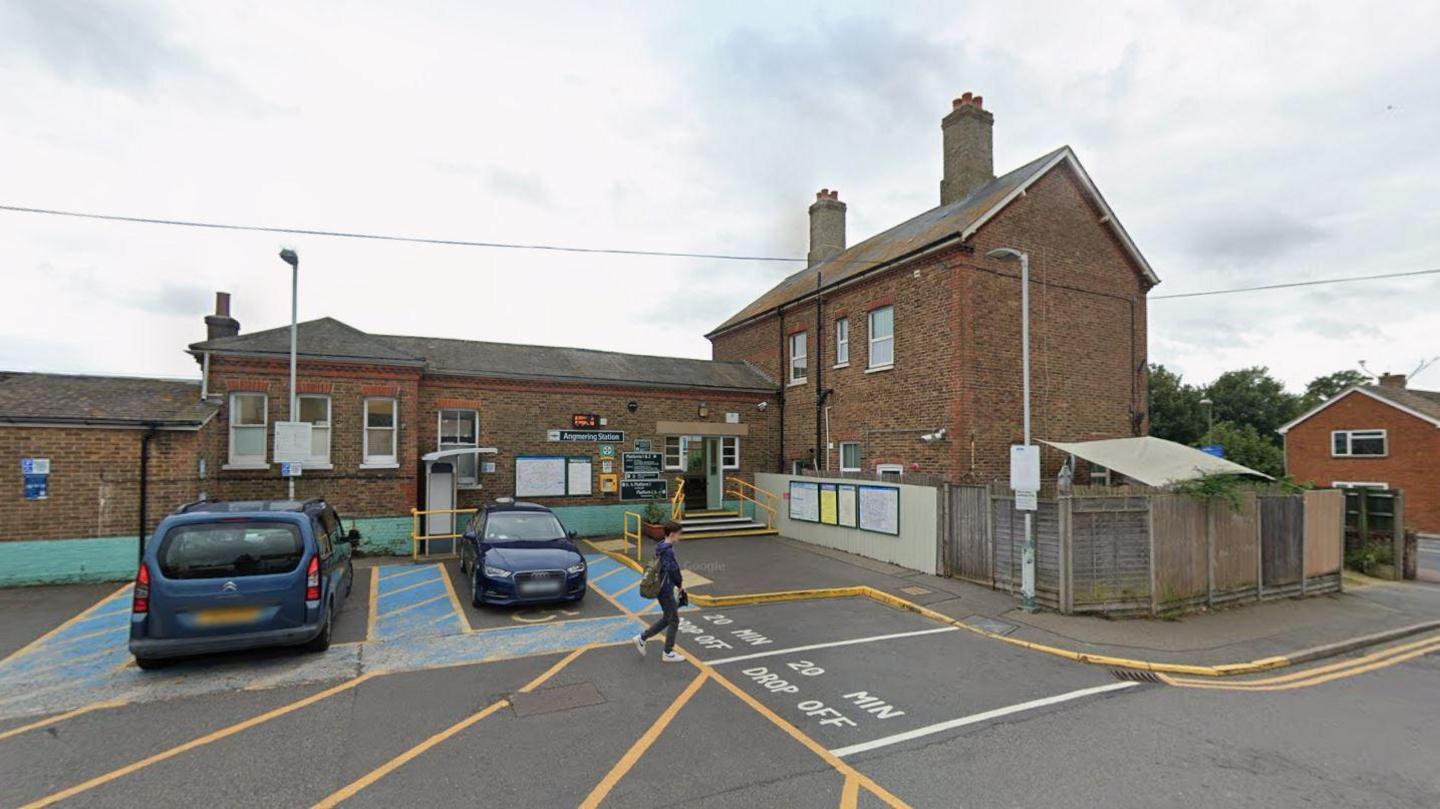 A brick building. It is a train station. The sky is grey.