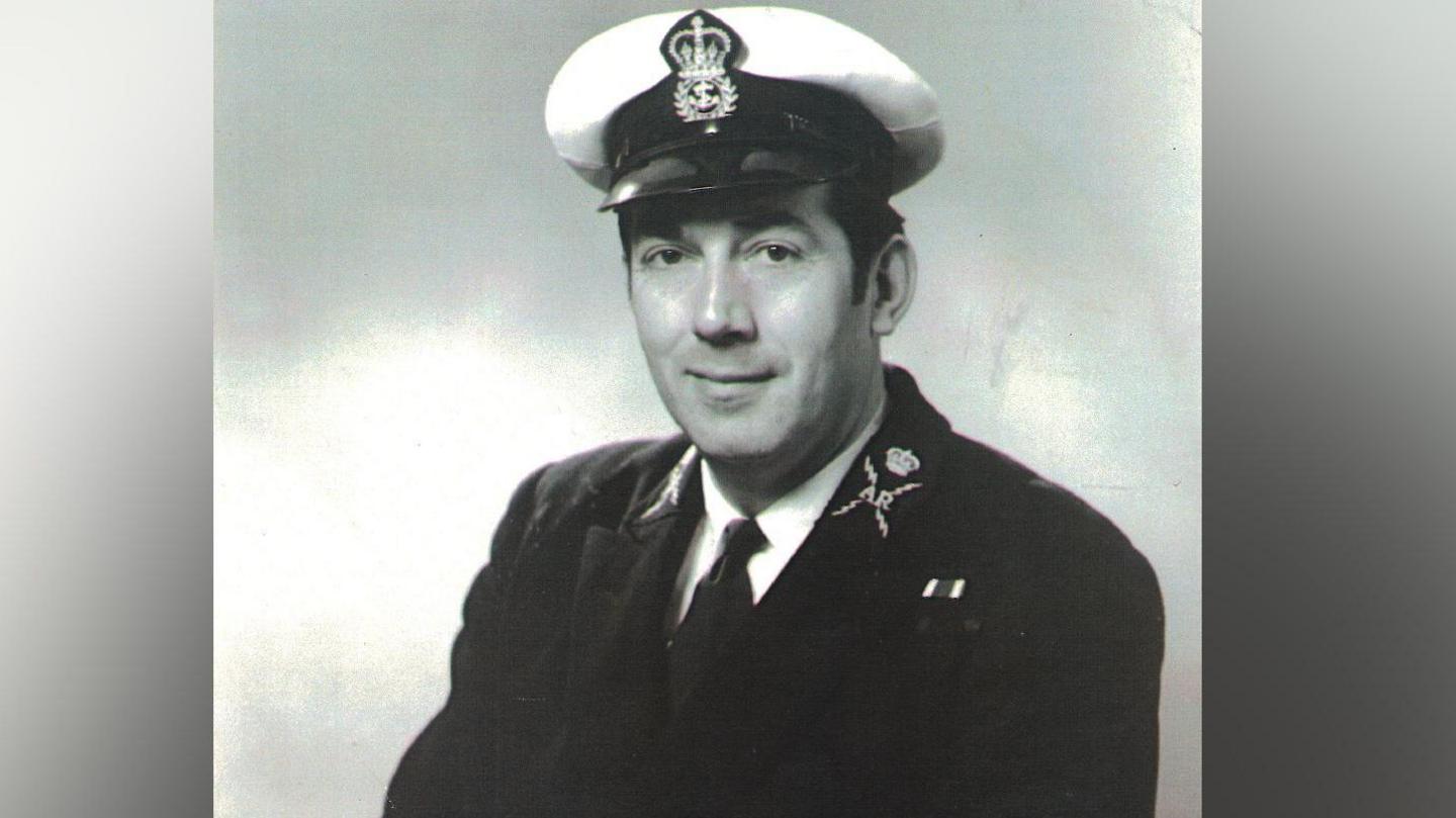 Black and white photo of Ernest Williams from when he was serving in the Royal Navy. He has on a Navy Uniform and hat.