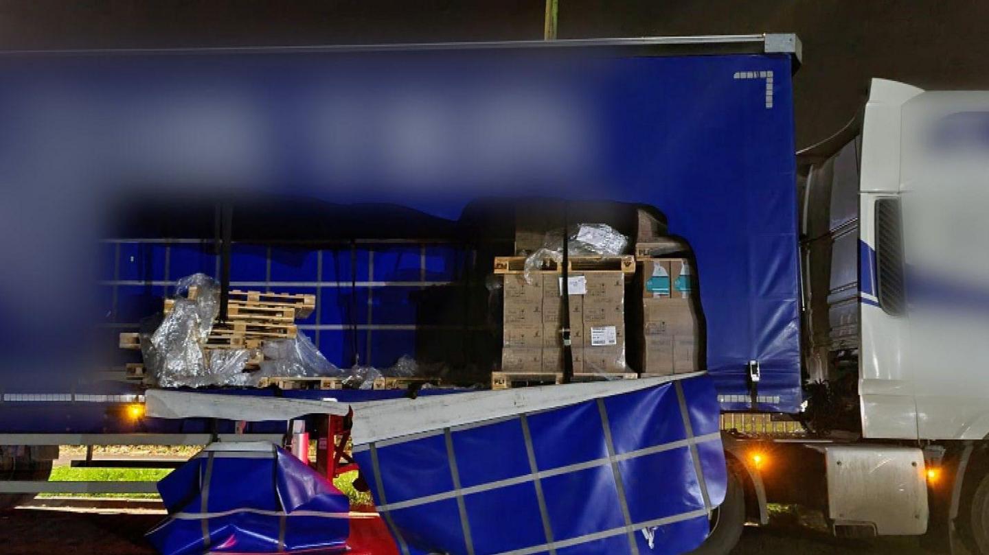 A lorry with its side curtain torn open and missing cargo