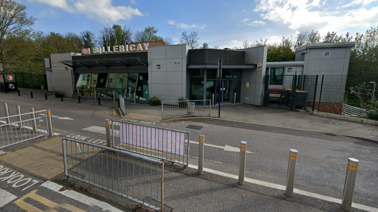 The entrance to Billericay Rail Station. The sky is blue and the road outside is visible. 