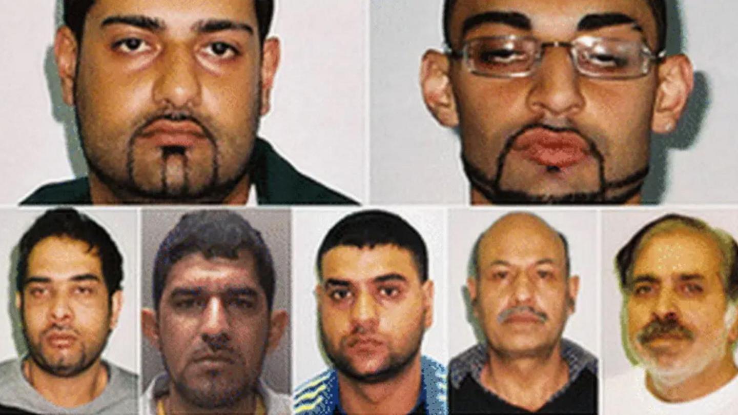 The faces of seven men with dark hair in front of white backgrounds. All have dark hair and moustaches and all but one have beards.