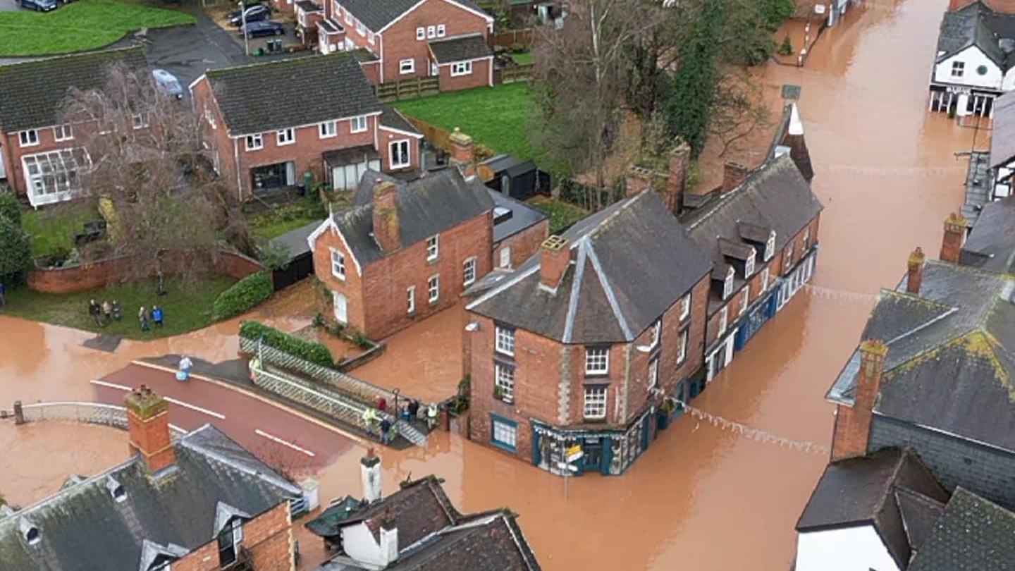 Flood water reaches houses and businesses in the streets of Tenbury Wells, with every road submerged in muddy water.