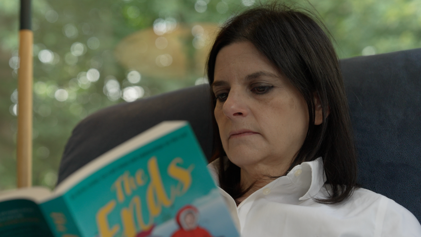 Sarah Johnson reading a book in her living room