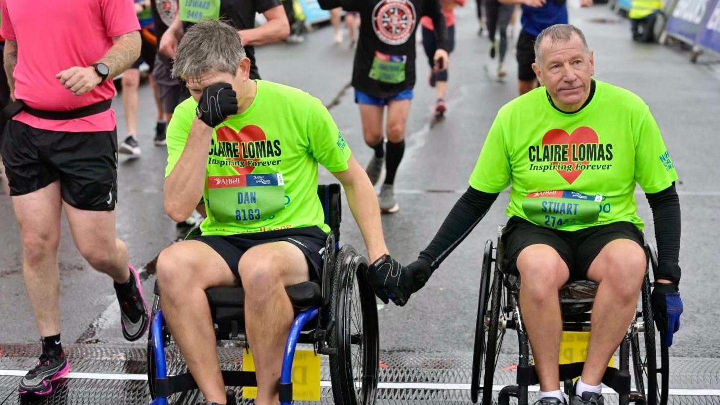 Two men in wheelchairs, one teared up, at the finish line of the race