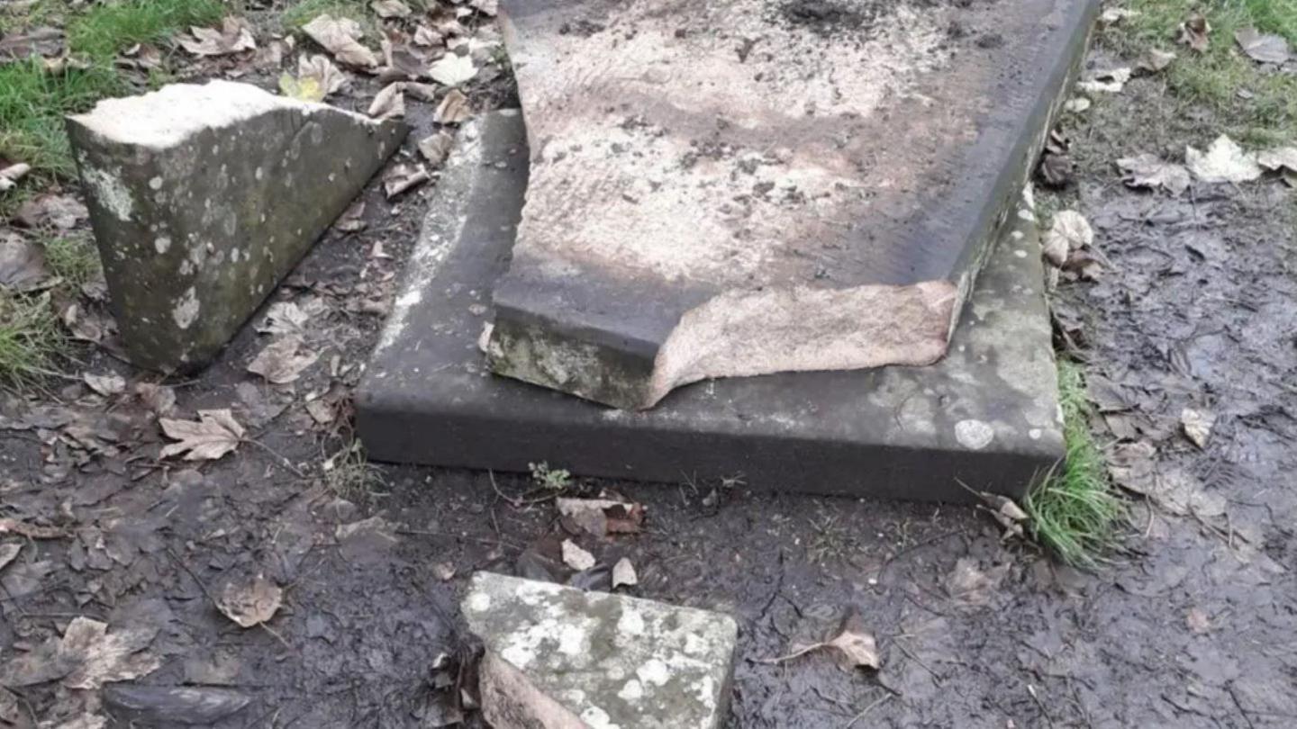 A gravestone, smashed into a number of large chunks