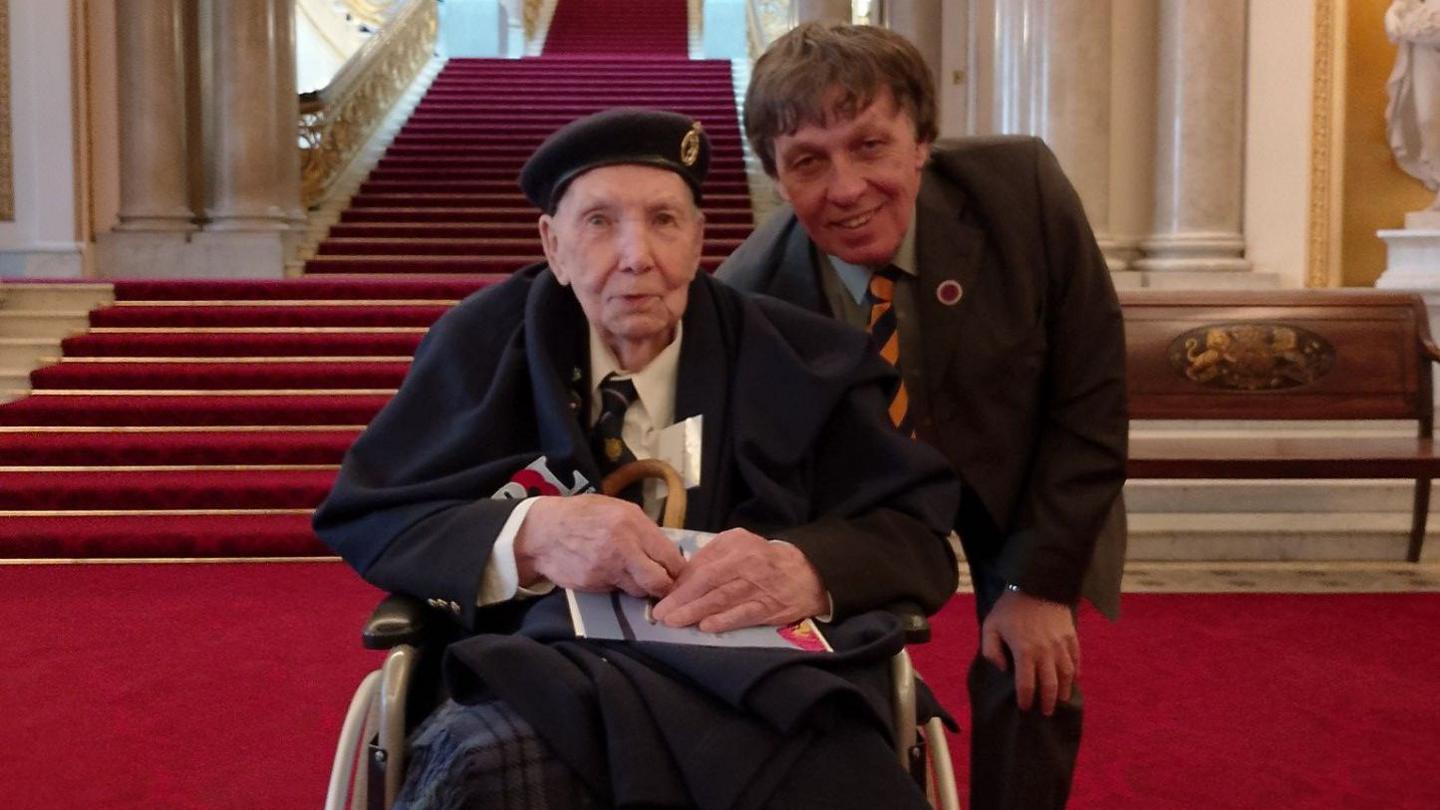 An elderly male war veteran sits in a wheelchair in a palace.