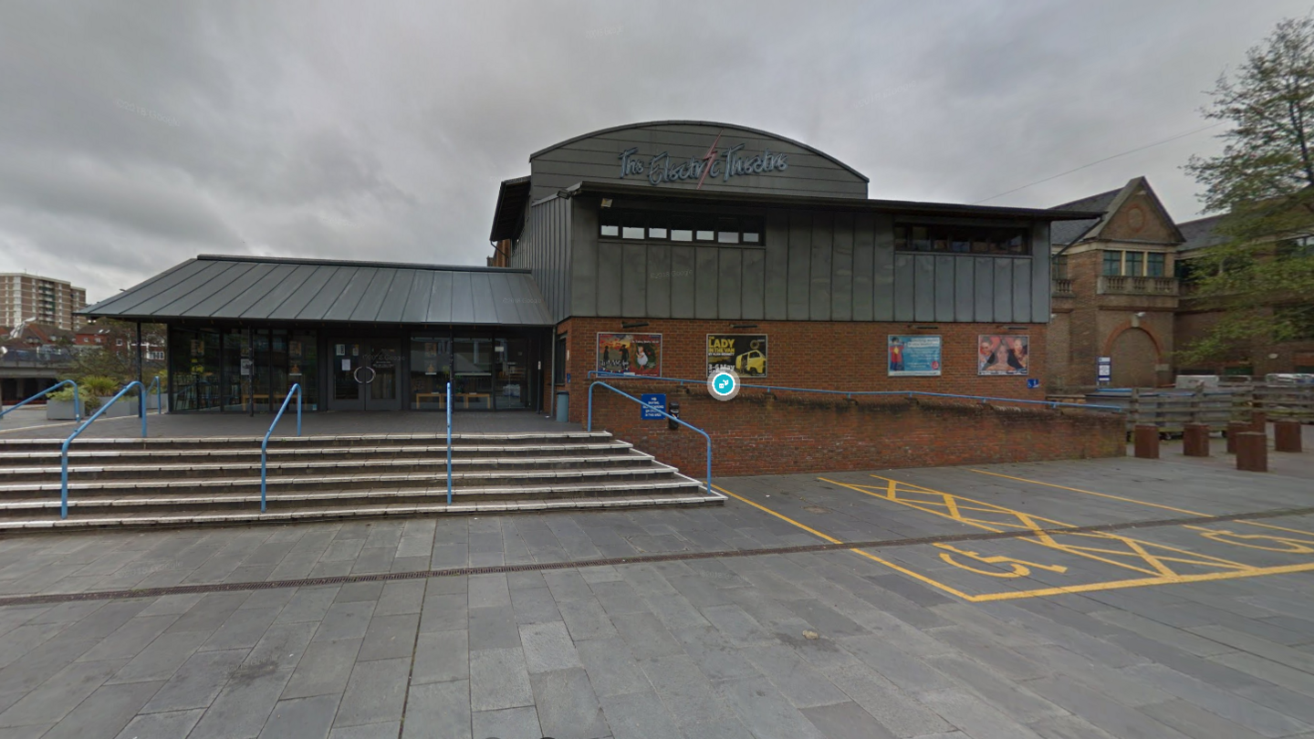 Exterior of the Electric Theatre in Guildford. Steps lead up to the main entrance and there is a sign saying 'Electric Theatre.' There are disabled parking spaces in front of the building.