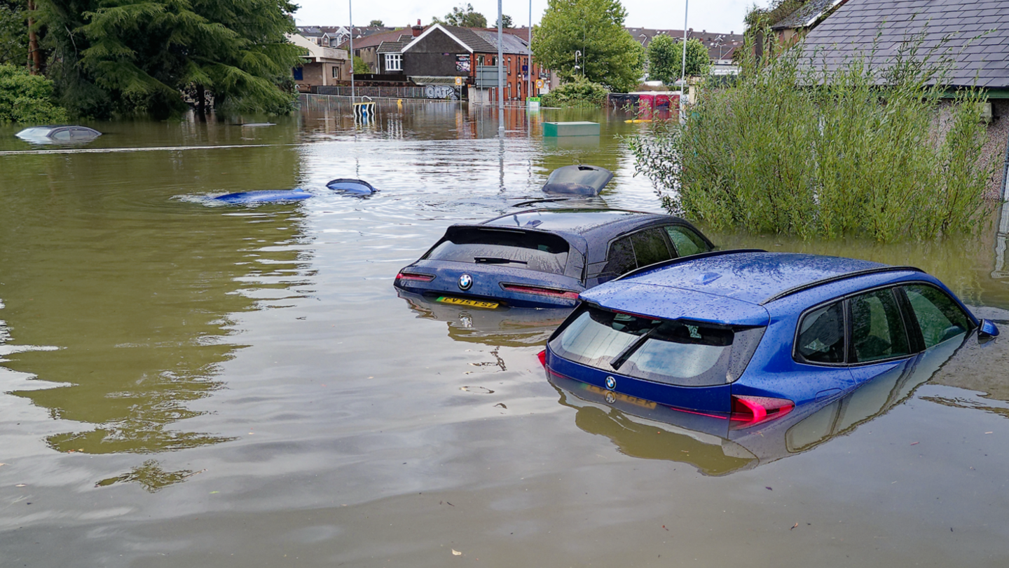 flood water half way up to a couple of cars.  Some cars in the distance totally submerged