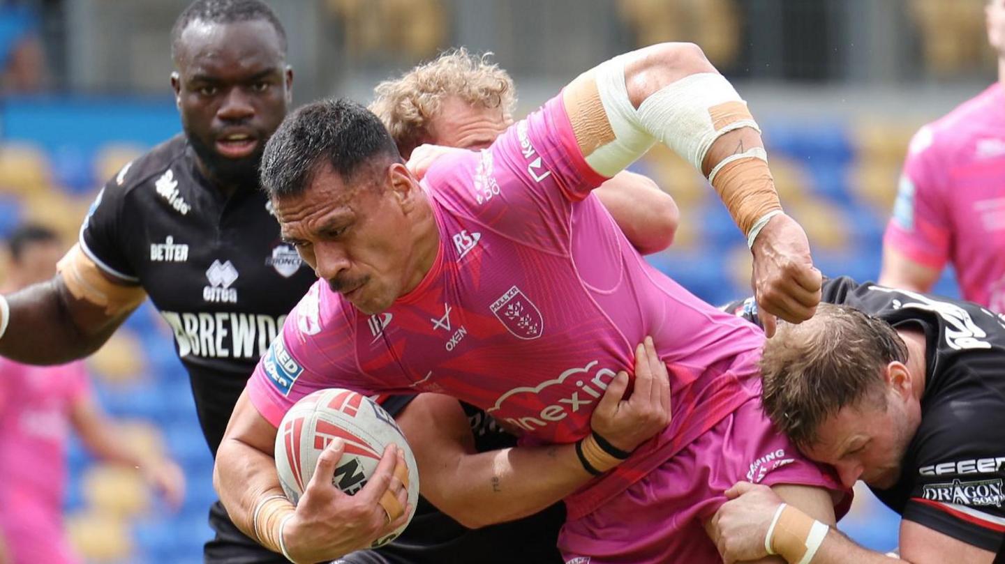 Sauaso Sue tries to break a tackle from London Broncos' Lewis Bienek for Hull KR with the ball wrapped under his arm